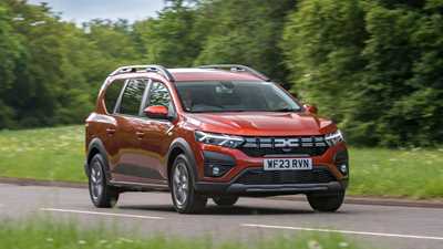 Dacia Jogger Hybrid (2023): front three quarter driving, country lane, orange car